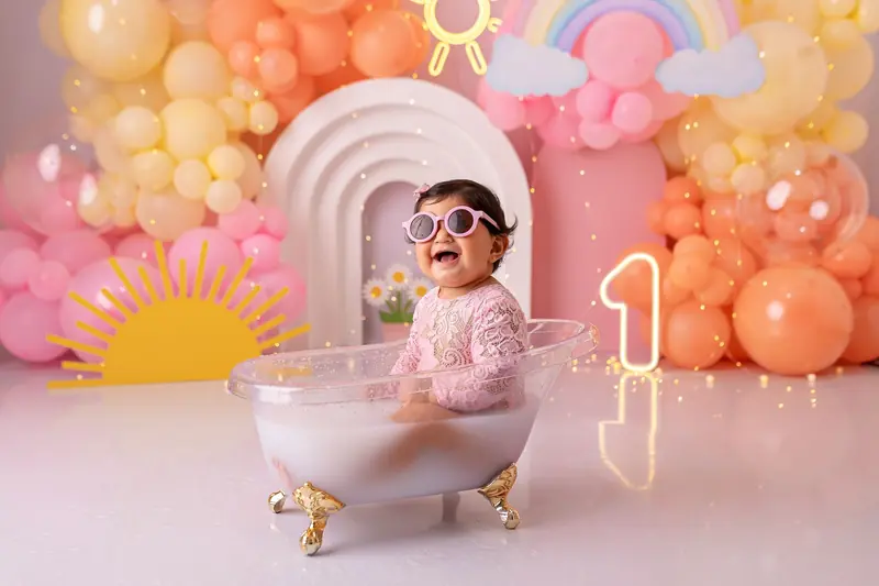 Baby enjoying a vibrant bath celebration with balloons and decor