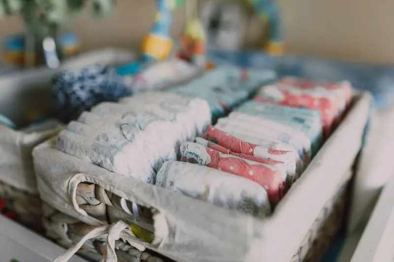 Close-up of neatly arranged colorful baby diapers in a woven basket, ideal for nursery organization
