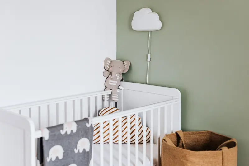 Modern baby room featuring a white crib, soft decor, and pastel accents