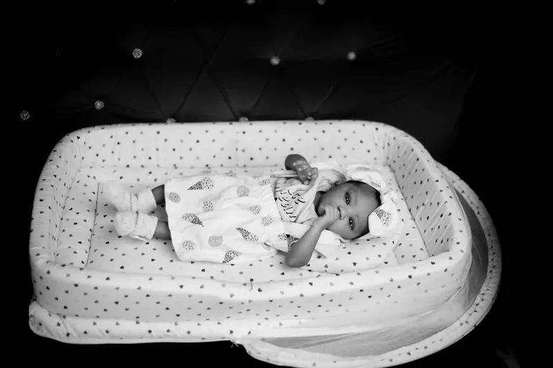 Adorable baby lying in a patterned crib, captured in elegant black and white