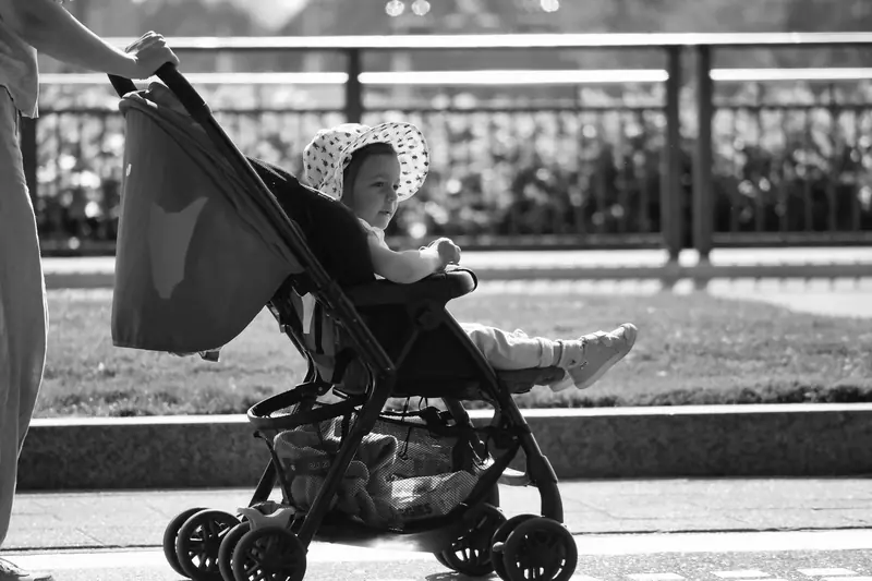 Adorable baby in a sun hat enjoys a stroll in a stroller, black and white urban setting